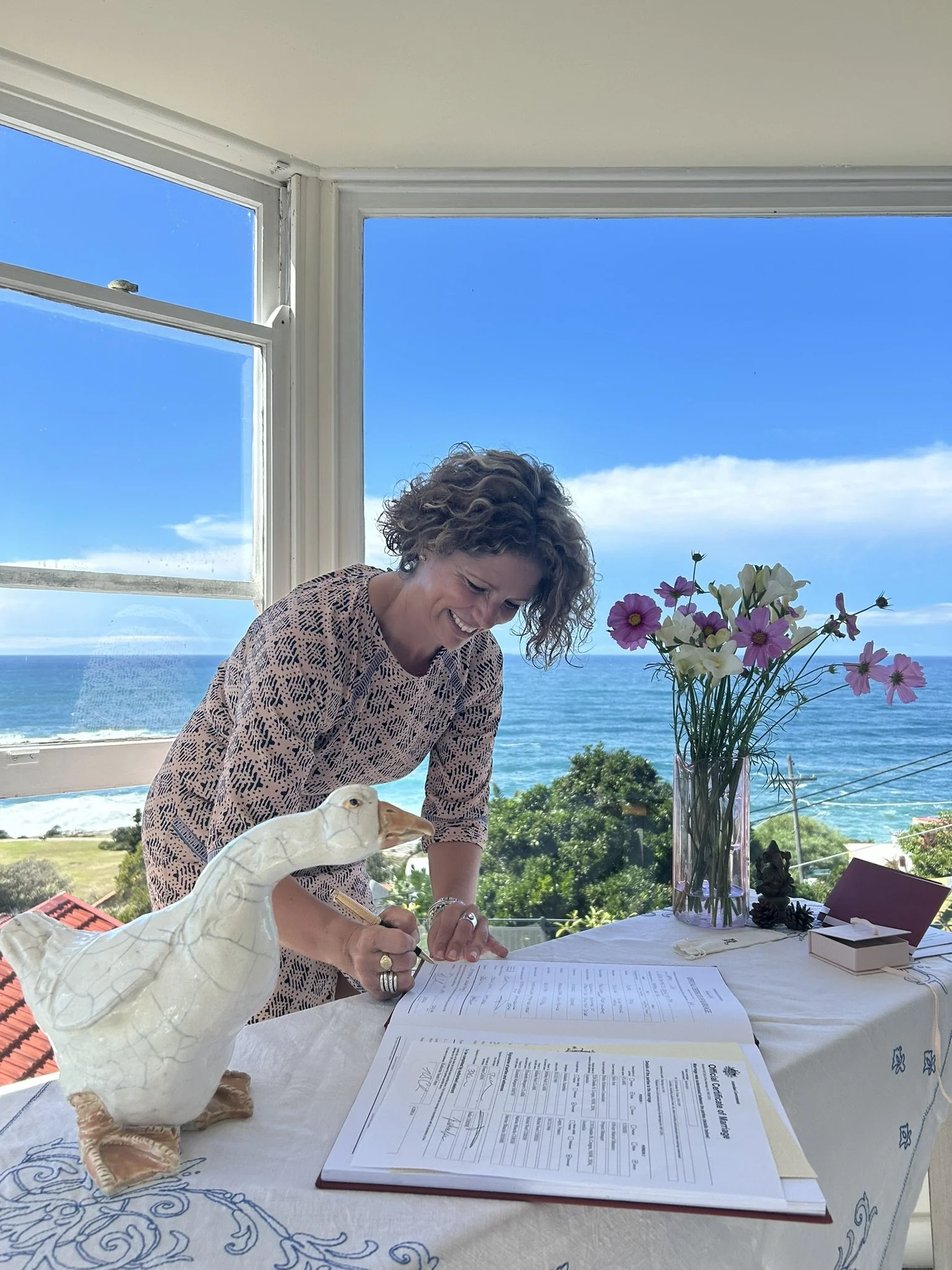 Marriage celebrant Kate Cohen signing marriage papers with ocean in background in Coogee in Sydney's Eastern Suburbs