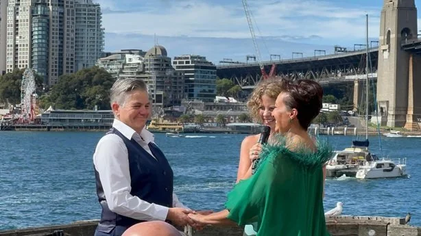 Sydney marriage celebrant Kate Cohen conducting a same-sex wedding ceremony on a wharf with the Sydney Harbour Bridge in the background