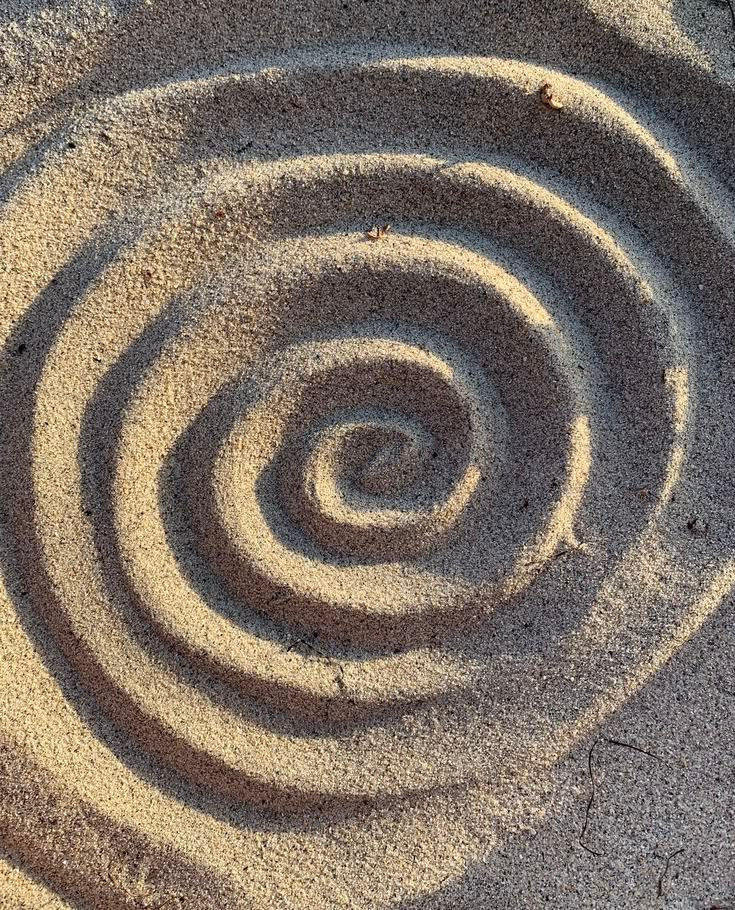 Sand pattern spiral drawn on the beach.