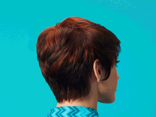 Side profile of a woman with short brown hair against a blue background, wearing a blue patterned shirt.