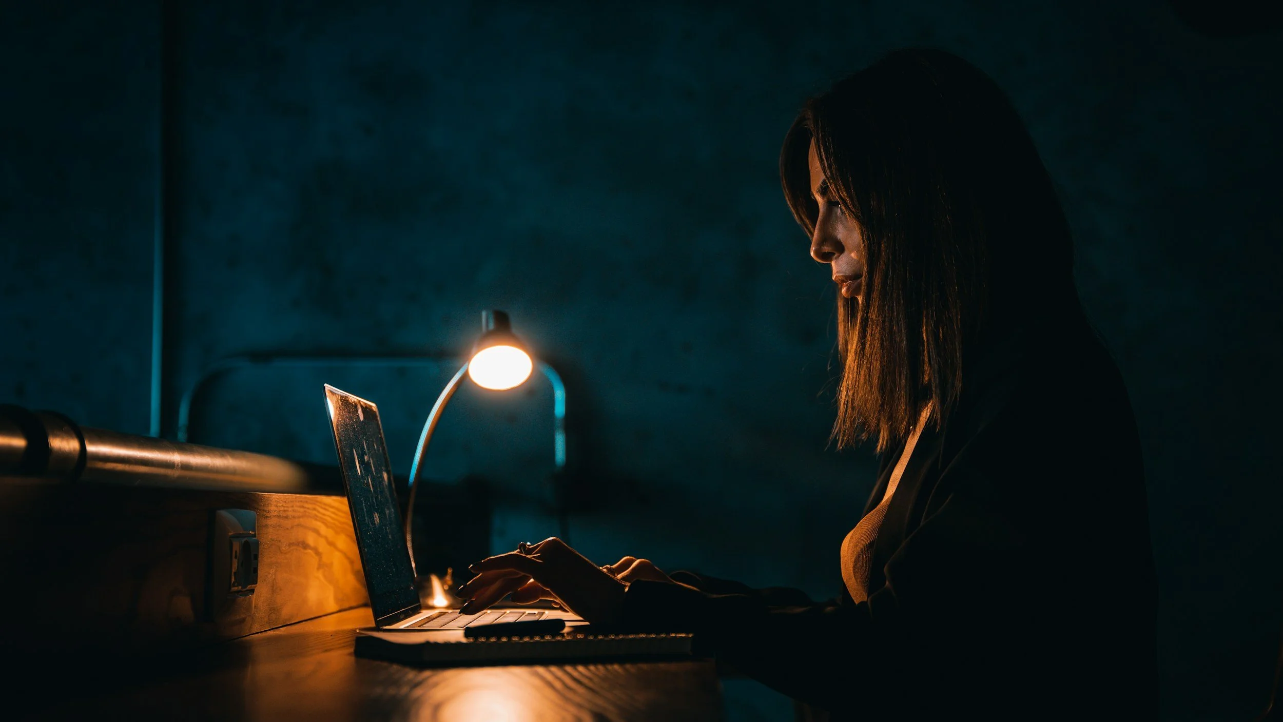 Woman at her desk late at night polishing a work presentation, illustrating ADHD and perfectionism in high-achieving women