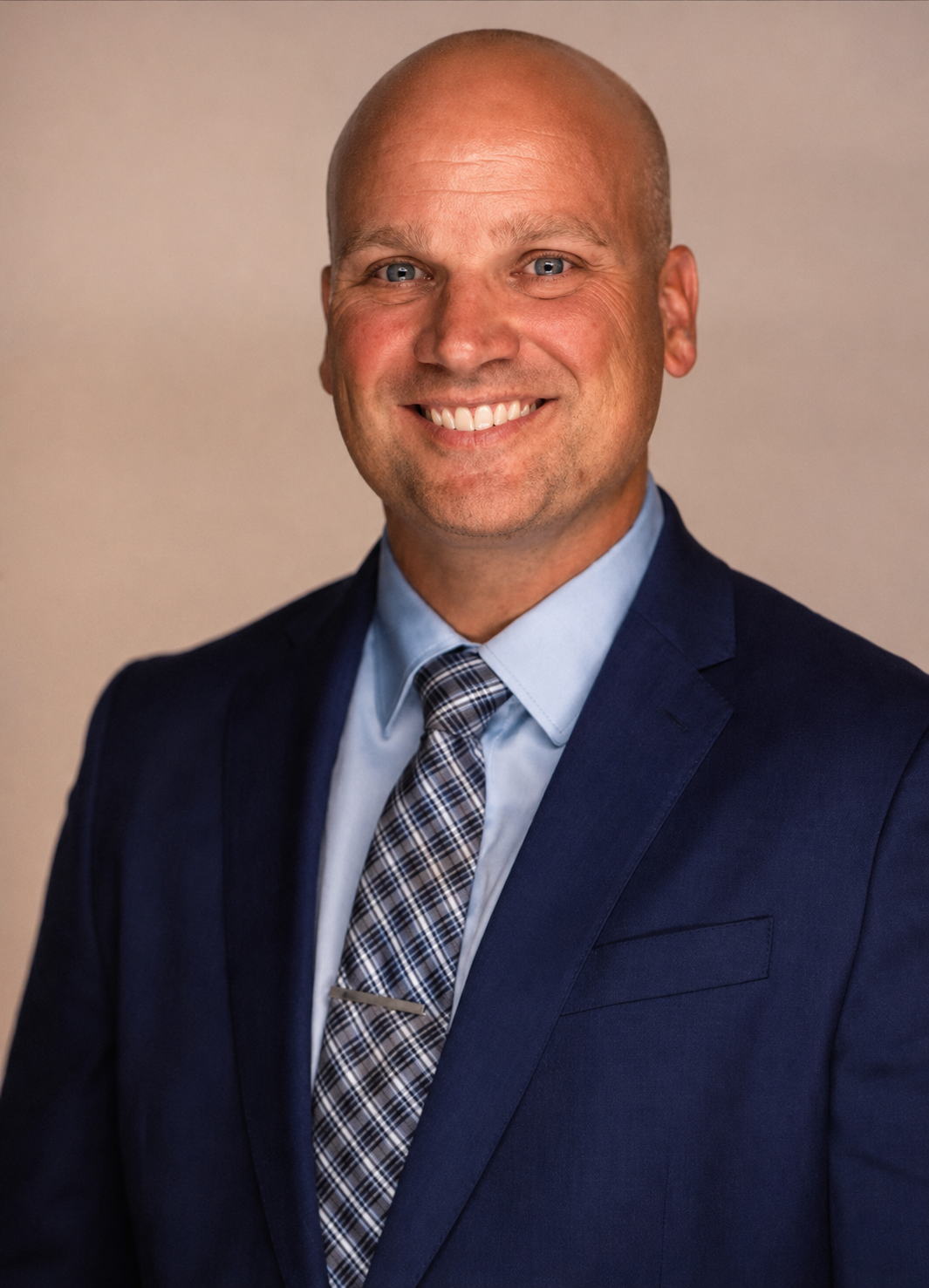 Headshot of a smiling Cody D. Edwards, light blue shirt, and patterned tie, against a neutral background.