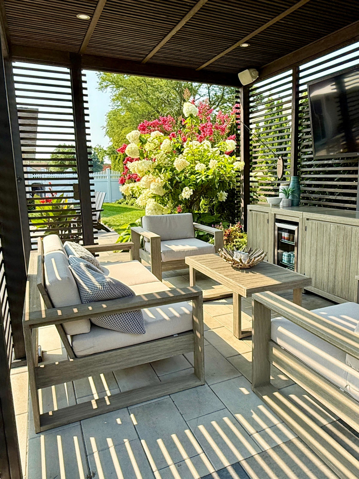 Custom backyard living area featuring a handcrafted sun-blocking roof, wood privacy screens, and a custom-built table and chairs.