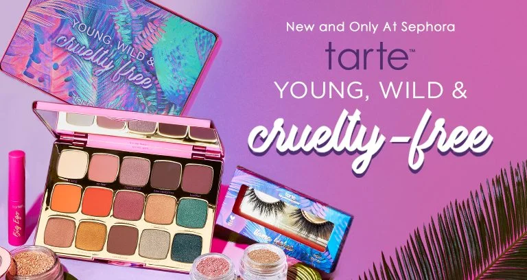 Sephora makeup display featuring Tarte's cruelty-free makeup palette, false eyelashes, and various cosmetic products on a purple background with palm leaf decoration.