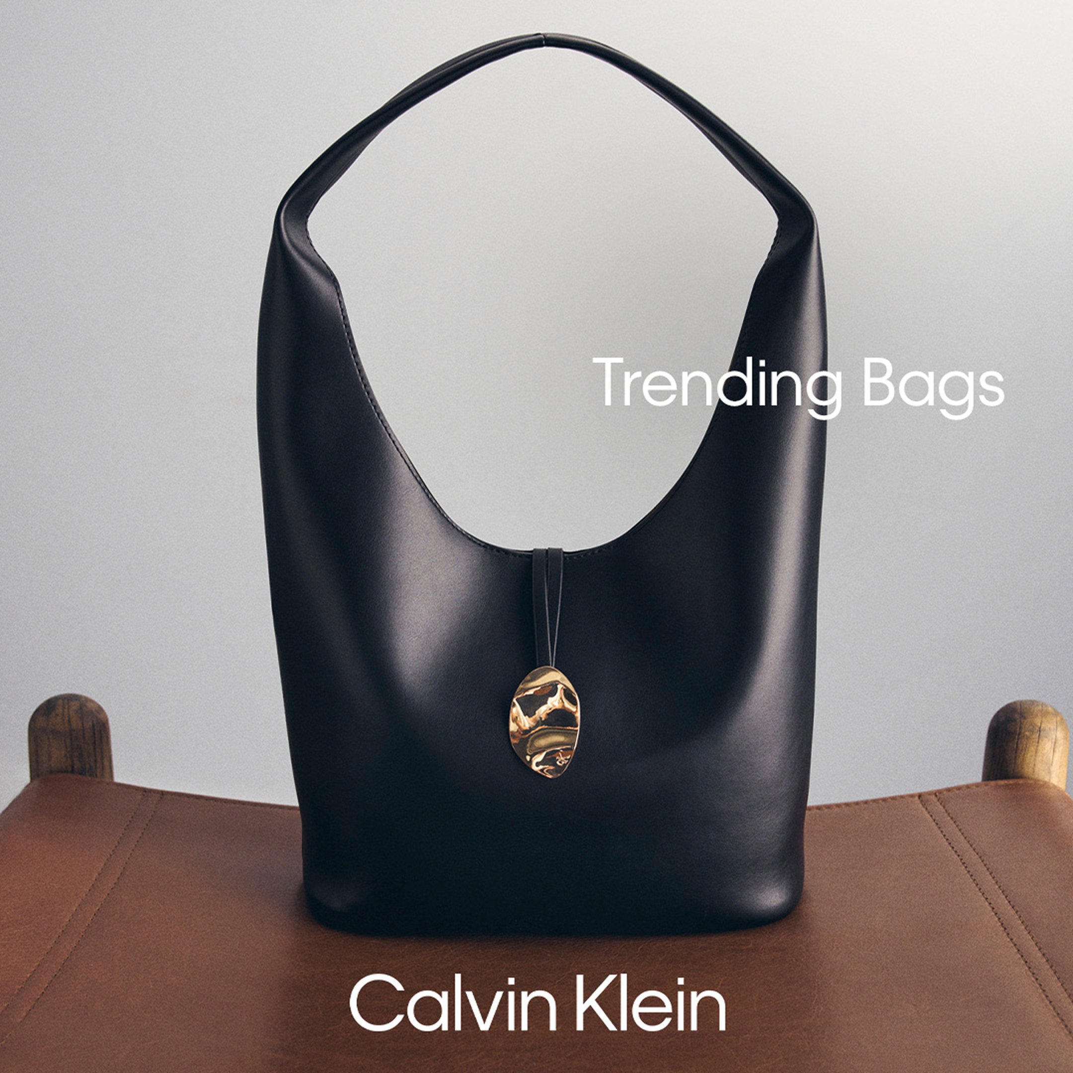 Close-up of a black Calvin Klein tote bag on a brown surface with the brand logo visible at the bottom.