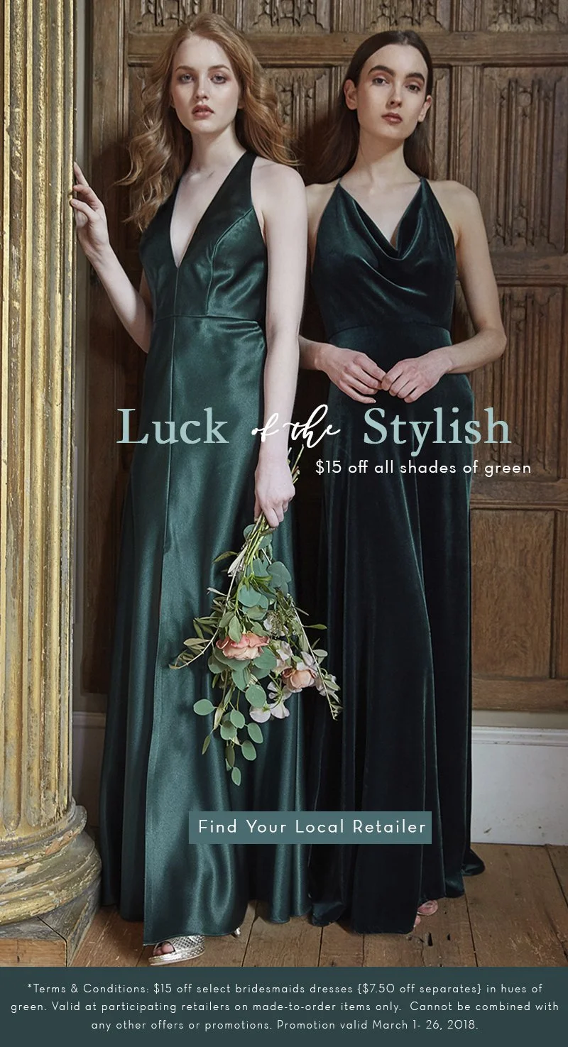 Two women in dark green dresses standing against a wooden wall, holding flowers, advertising a sale on green bridesmaid dresses.