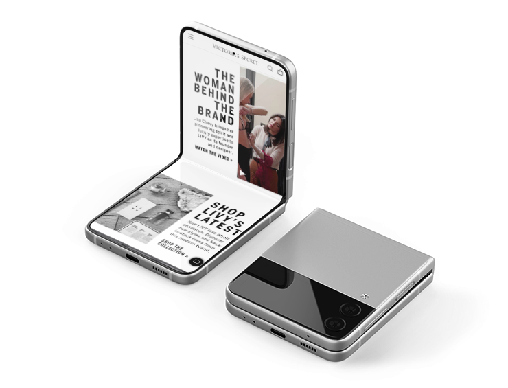 Two foldable smartphones with screens displaying fashion-related content, placed on a white surface. One phone is open showing a woman and text, the other is closed.