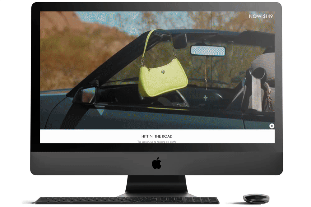 Computer monitor displaying a website with a photo of a car's interior showing a lime green handbag hanging from the rearview mirror, with a blurred scenic background outside the car.