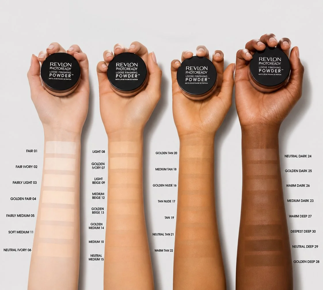 Four arms of different skin tones holding Revlon loose setting powders, with swatches of various foundation shades labeled from light to dark beside each arm.