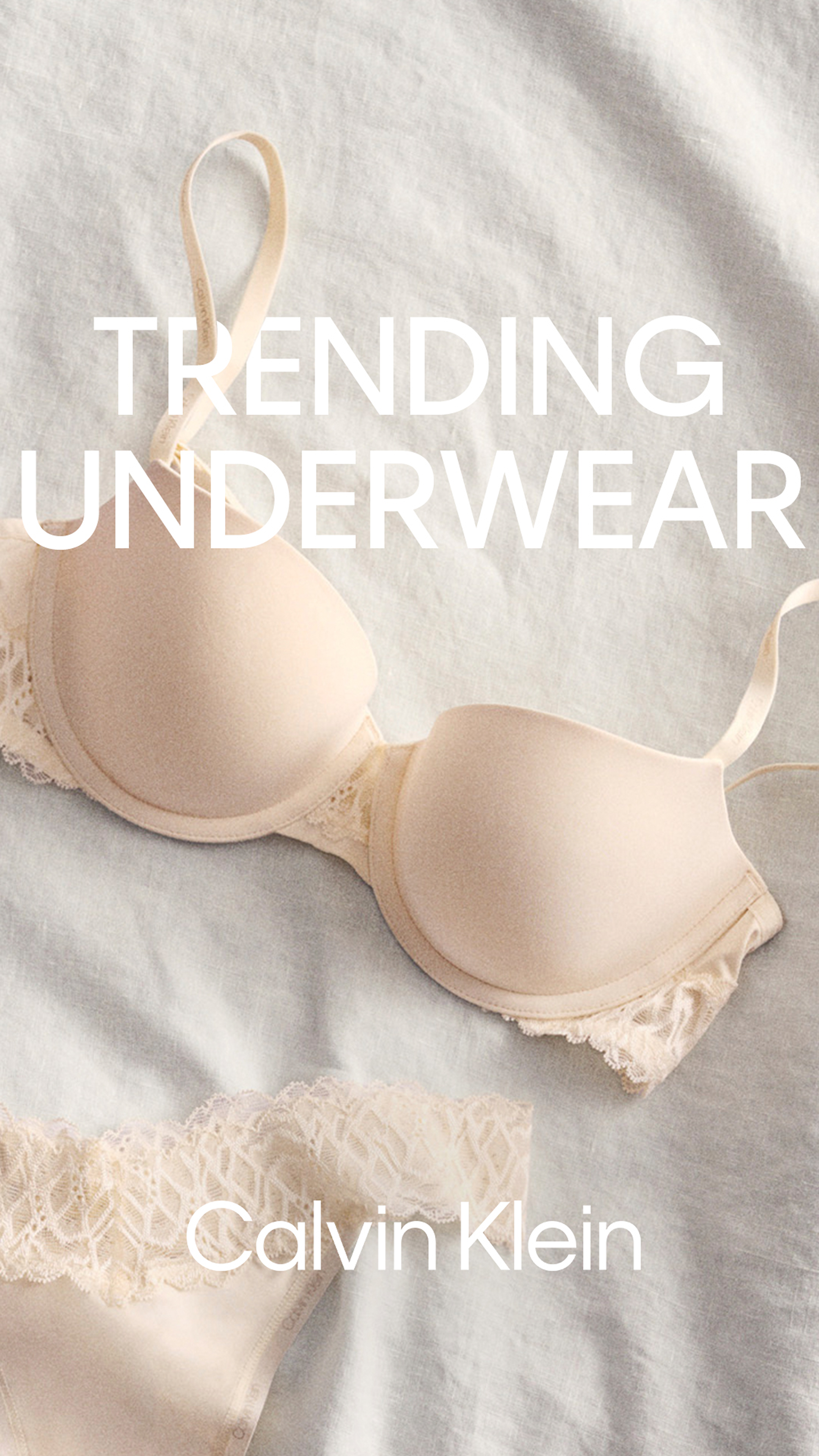 A nude-colored Calvin Klein bra with lace detailing on a light-colored fabric background.