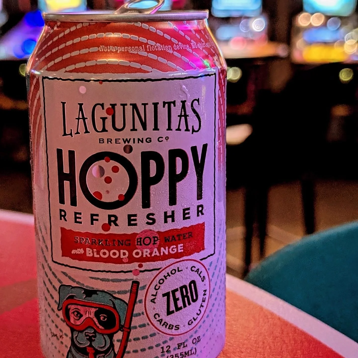 Lagunitas Hoppy Refresher on the bar at 403 Club with colorful arcade lighting in the background.