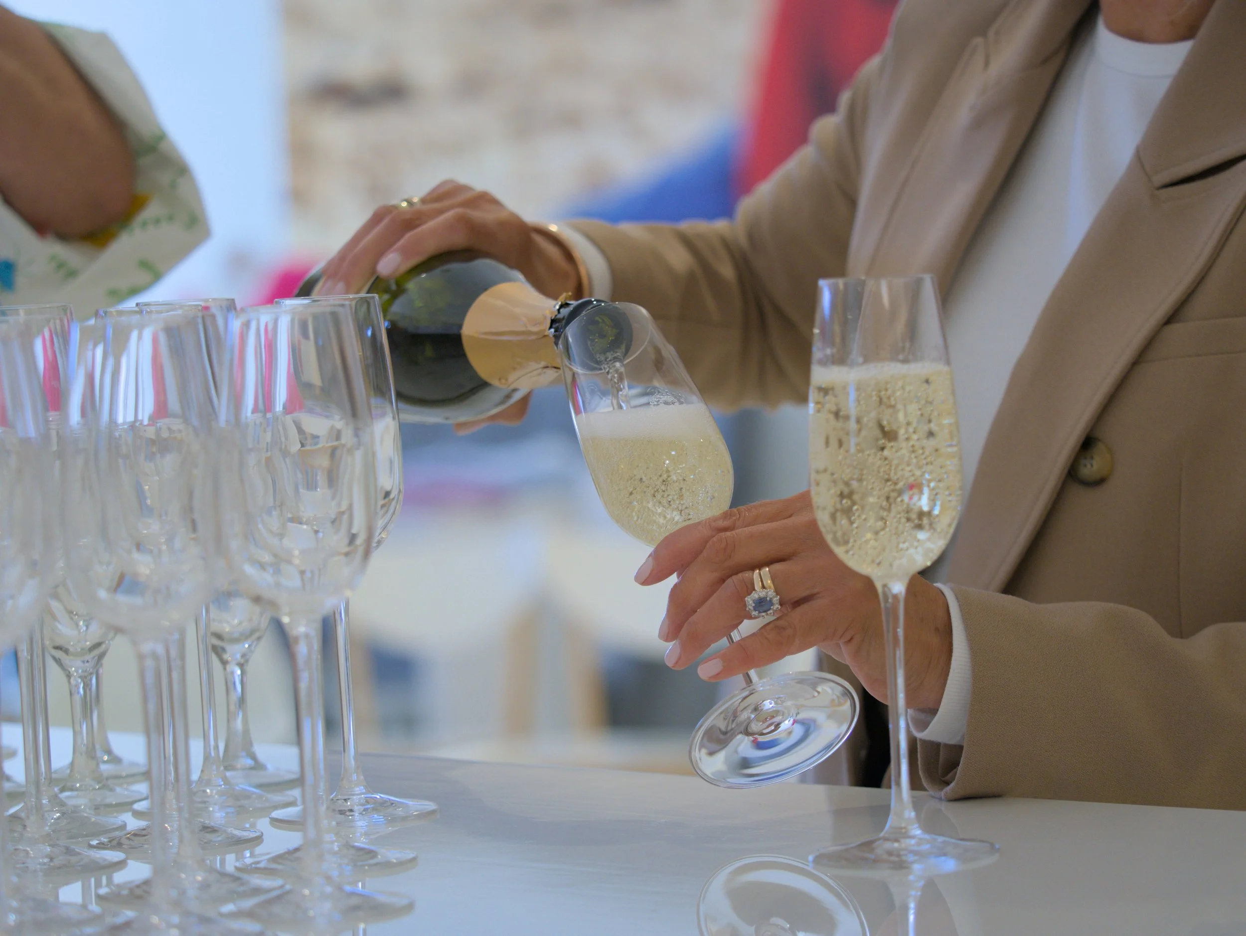 Person pouring champagne into flutes at a celebration or event.