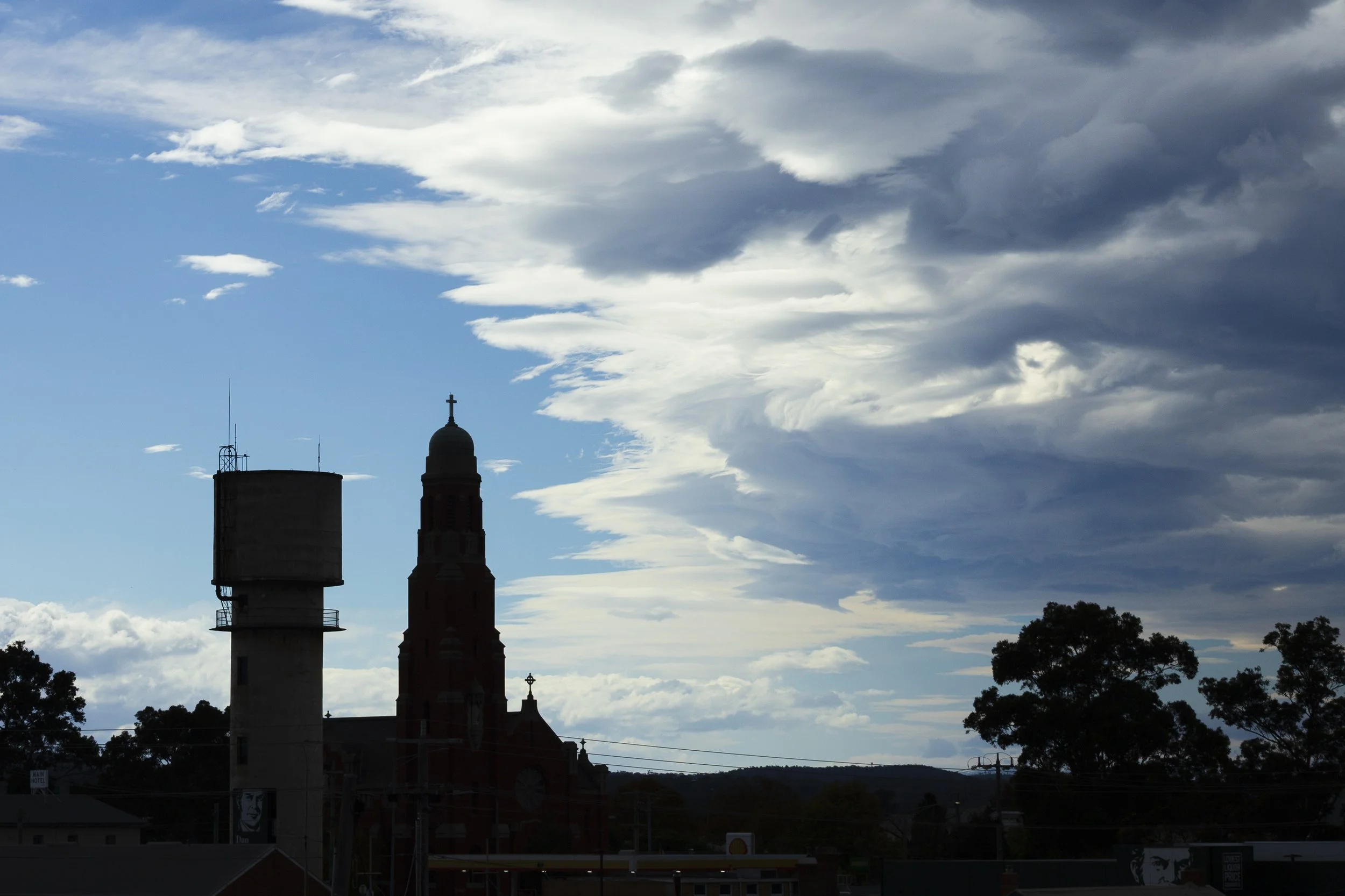 St Mary's bell tower and the Bairnsdale water tower silhouetted under storm clouds