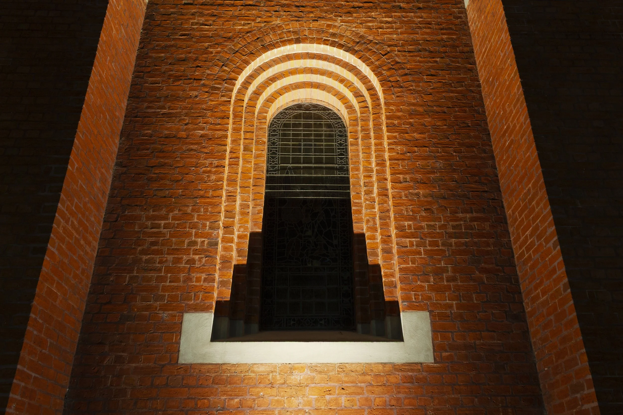 Stepped brick arch around a window at St Mary's Church, Bairnsdale, lit at night