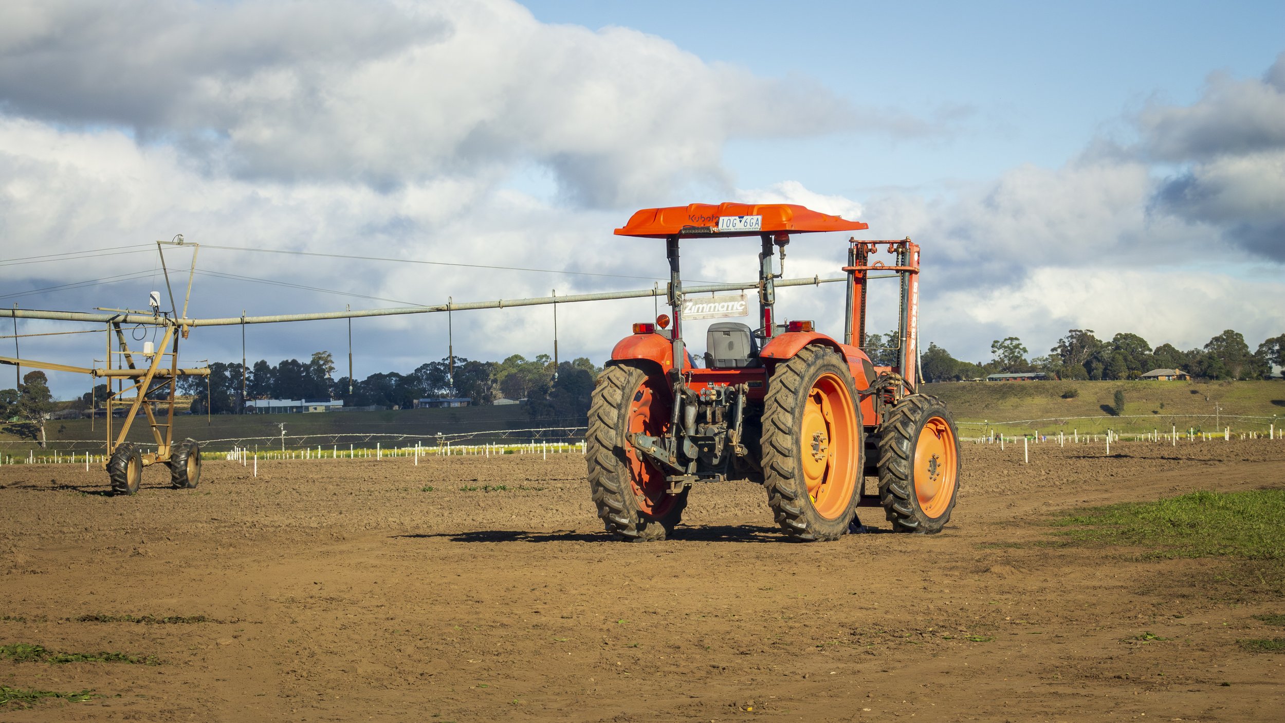 A tractor stands beside an irrigation system in a cultivated field.