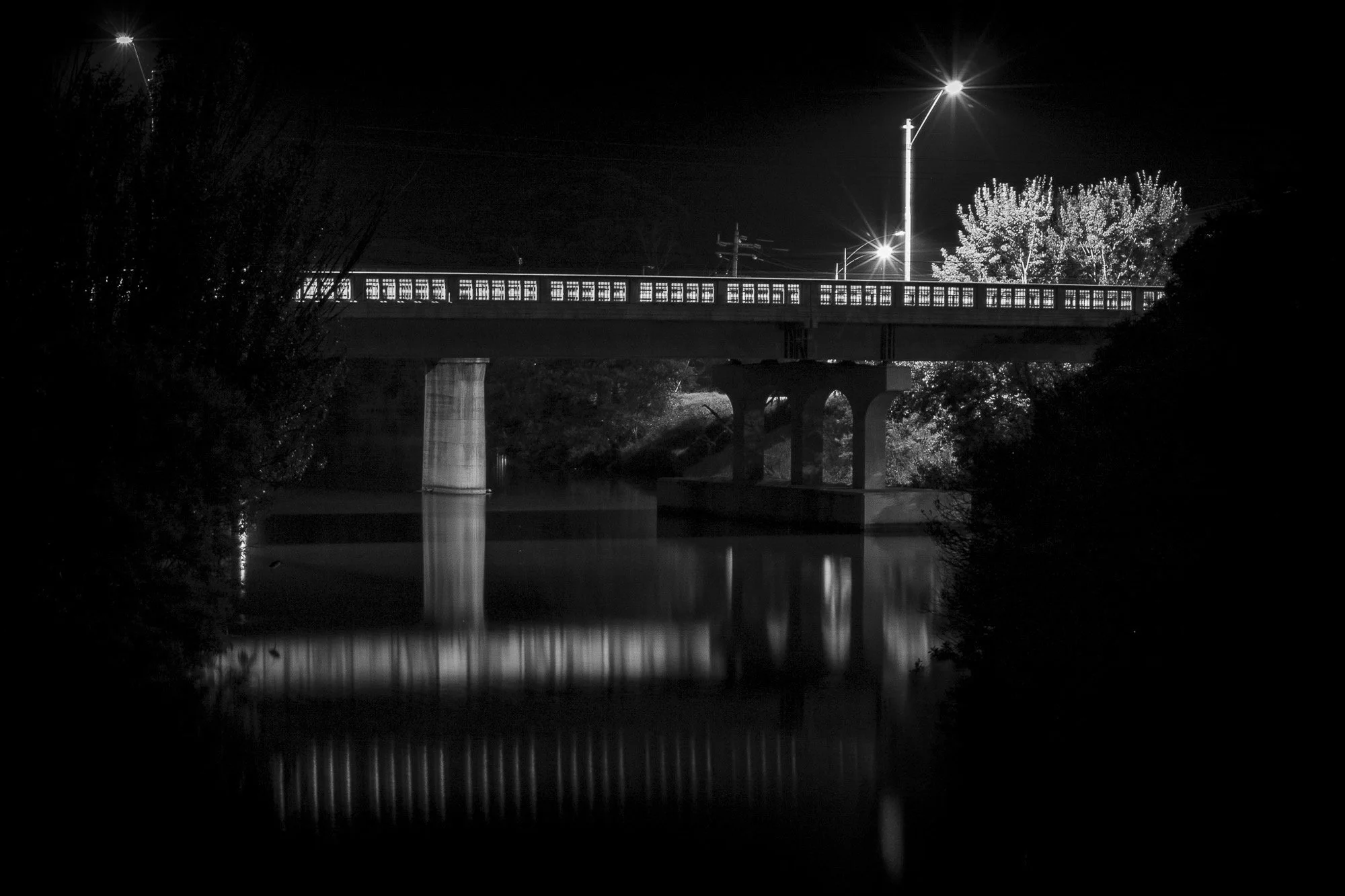 The Mitchell River Bridge reflected in the darkness of the river.