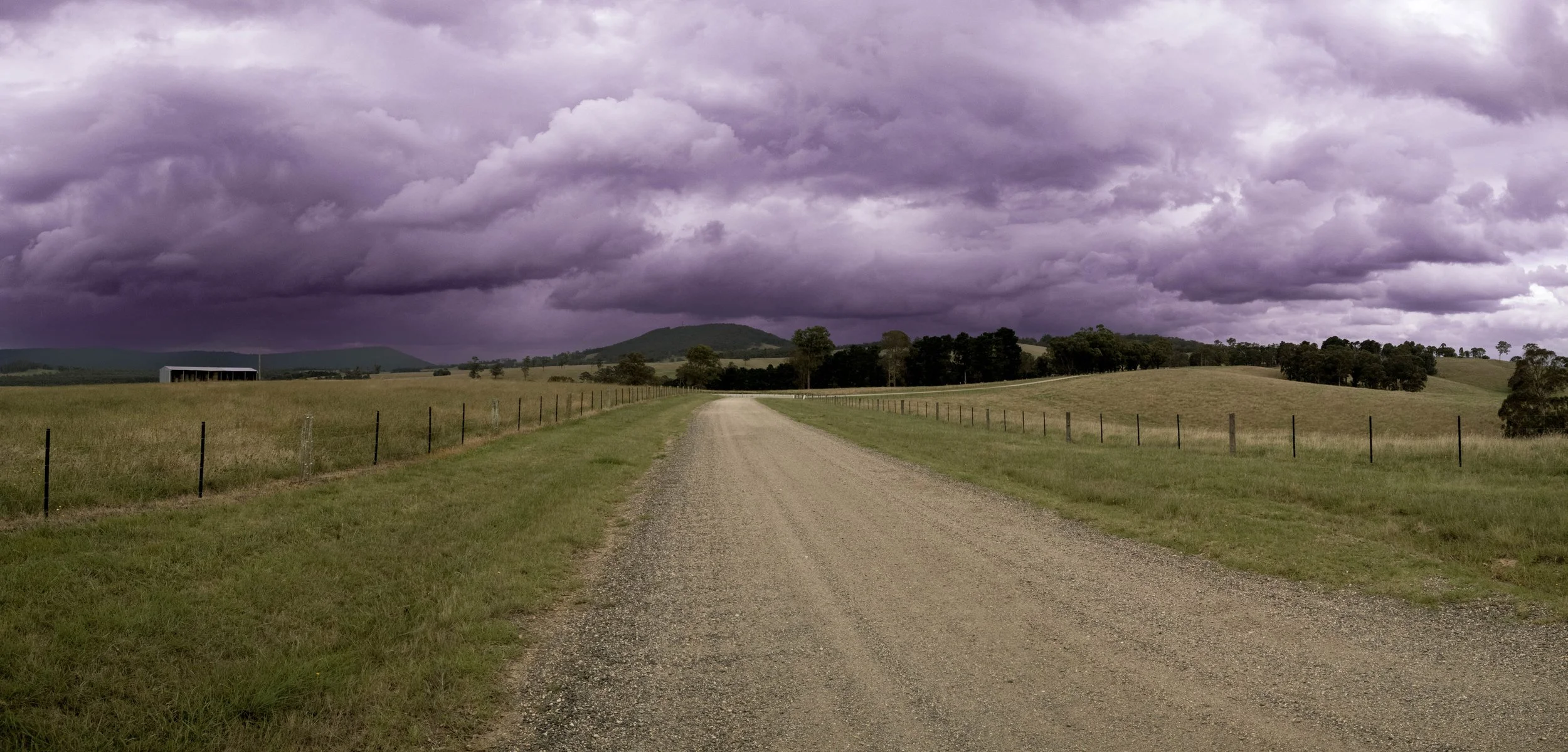 A country road disappears beneath a gathering storm.