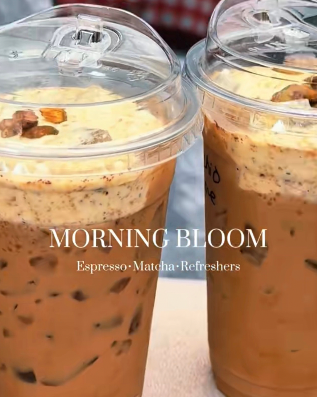Two plastic cups filled with iced coffee topped with whipped cream and sprinkled with cinnamon, with a clear plastic lid on each. The text on the image reads "Morning Bloom," and below it, "Espresso, Matcha, Refreshers."