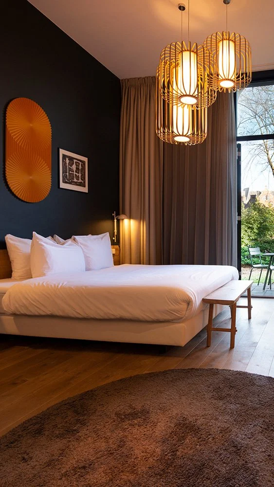 Bedroom with a large bed, white bedding, nightlight, ceiling lights, window, patio with outdoor seating, wall decor, rug, and curtains.