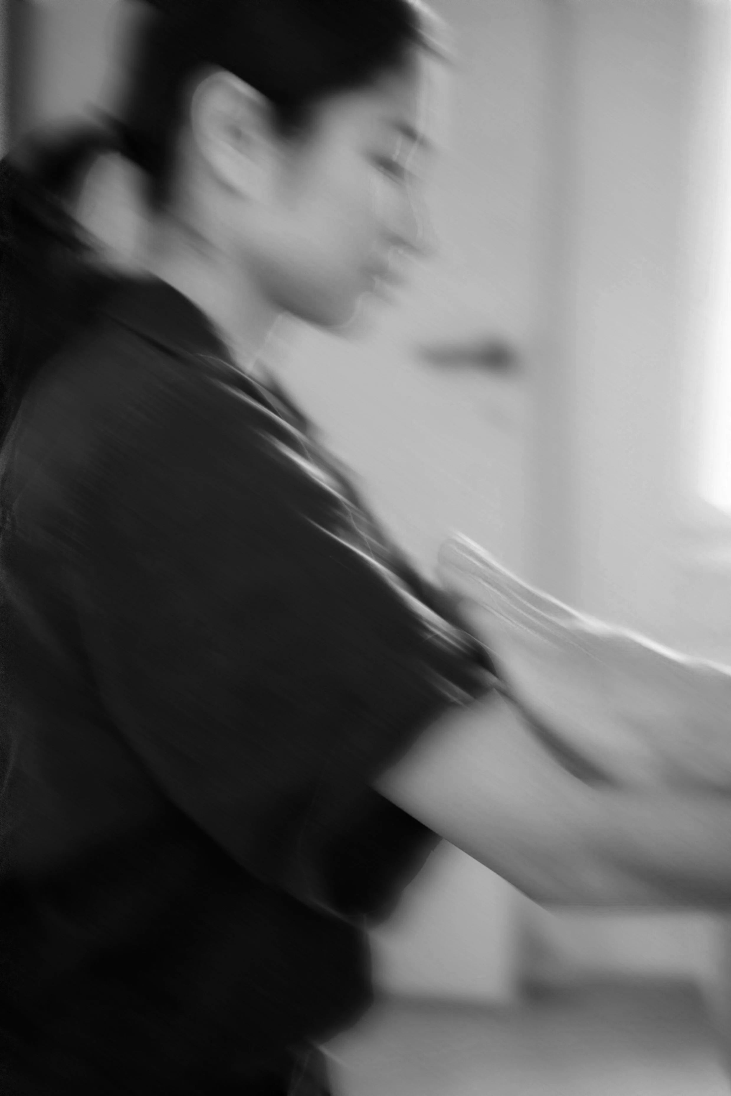 Black and white photo of a woman with glasses, with a side profile, blurry and out of focus.