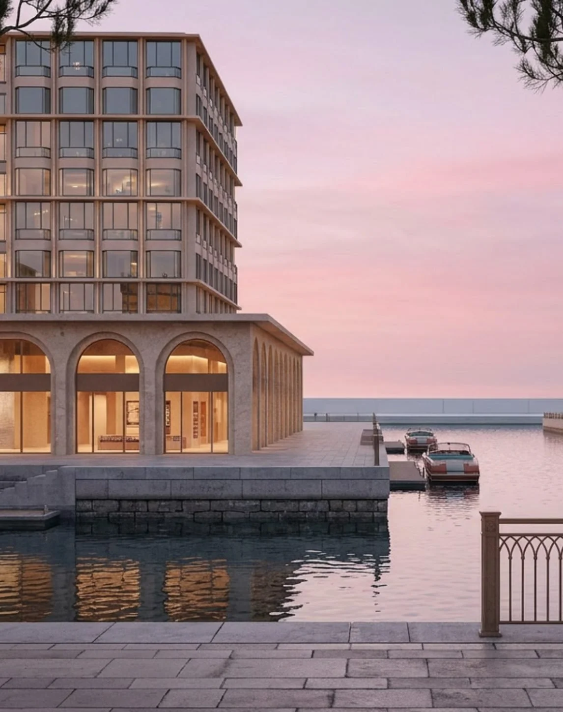 A modern apartment building by the water at dusk, with boats docked at the waterfront and a pink and purple sky.