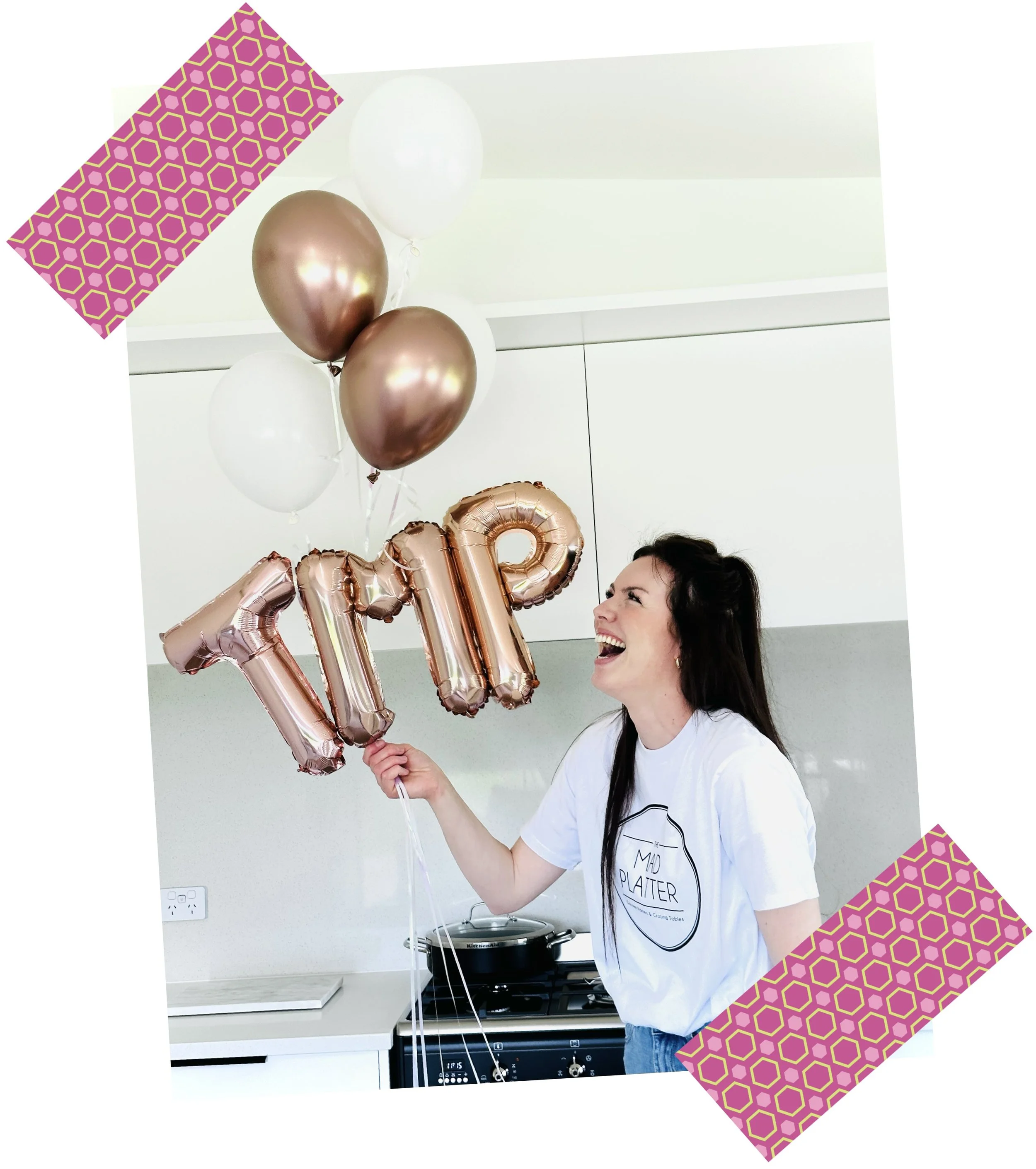 Woman celebrating holding balloons spelling 'IMP' in a kitchen.