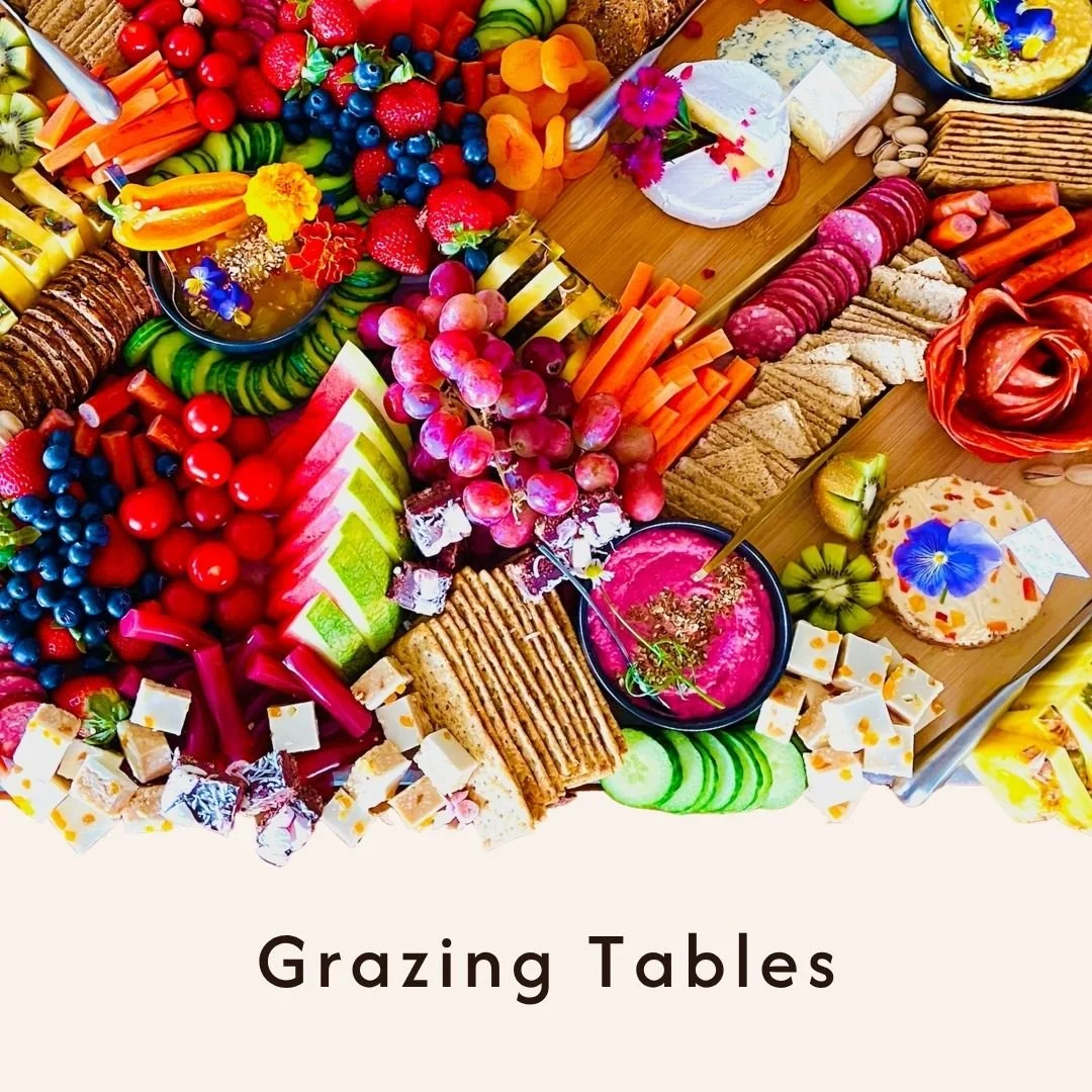 Overhead view of a table filled with an assortment of colorful fruits, cheeses, crackers, vegetables, and charcuterie, arranged for grazing or snacking.