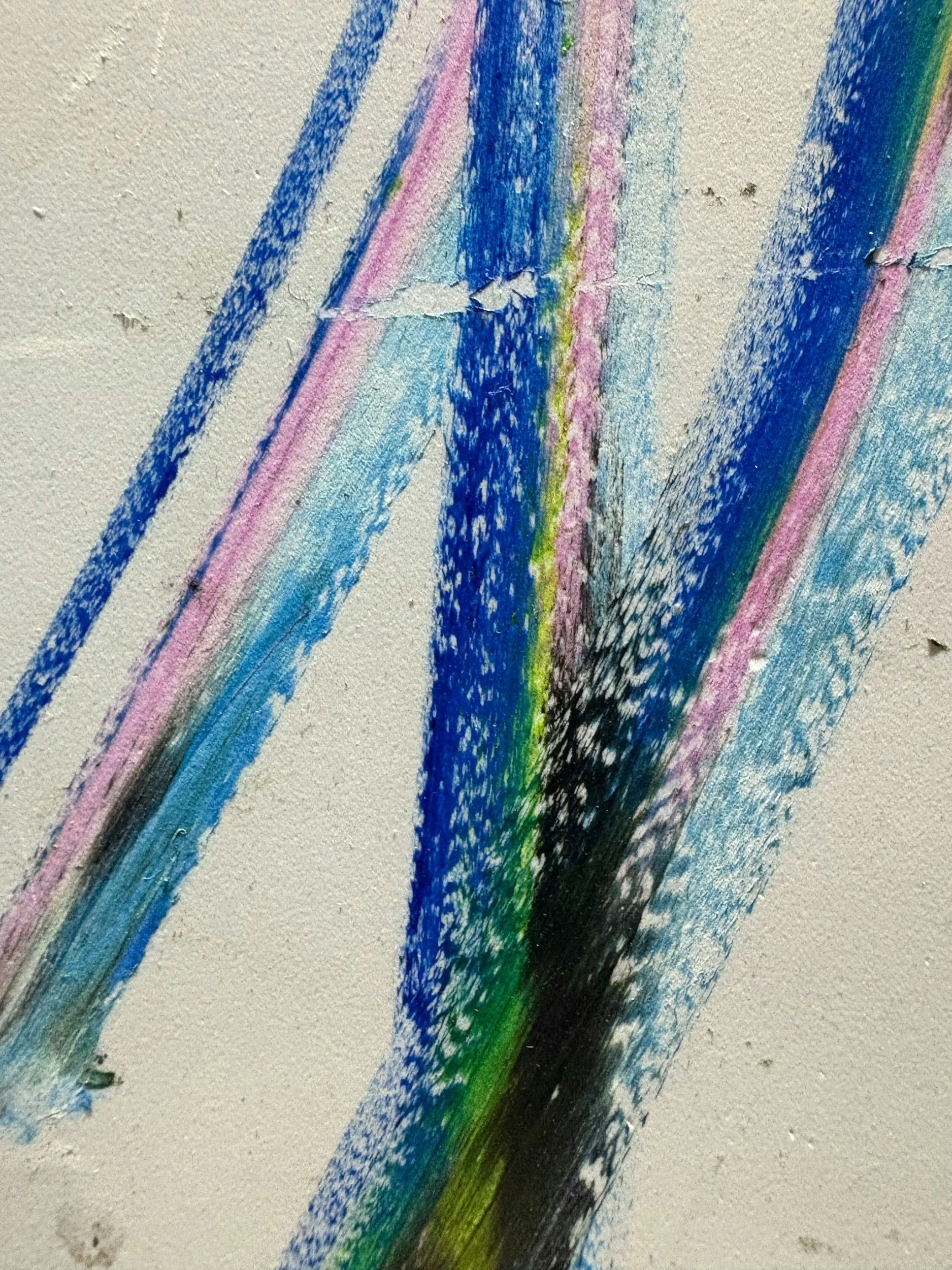 Colorful crayon scribbles on white paper, primarily blue, pink, black, and green.