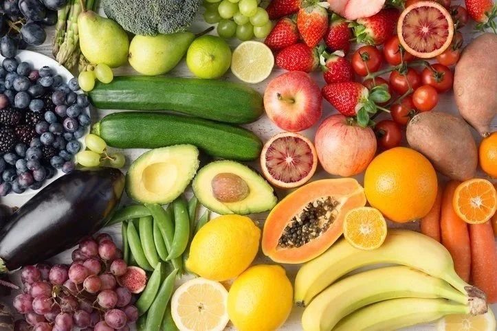 A variety of fresh fruits including blueberries, grapes, avocado, lemon, cucumber, apples, papaya, bananas, strawberries, oranges, kiwi, and carrots.