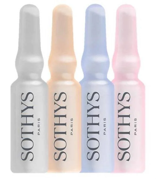 Four bottles of SOINS Paris skincare product in white, peach, blue, and pink colors arranged in a row.
