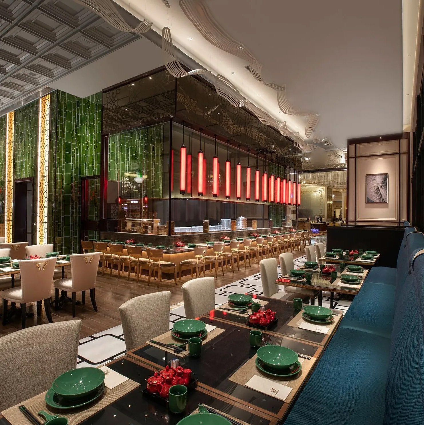 Elegant restaurant interior with green and white tableware, modern decor, and a bar with hanging red lights.
