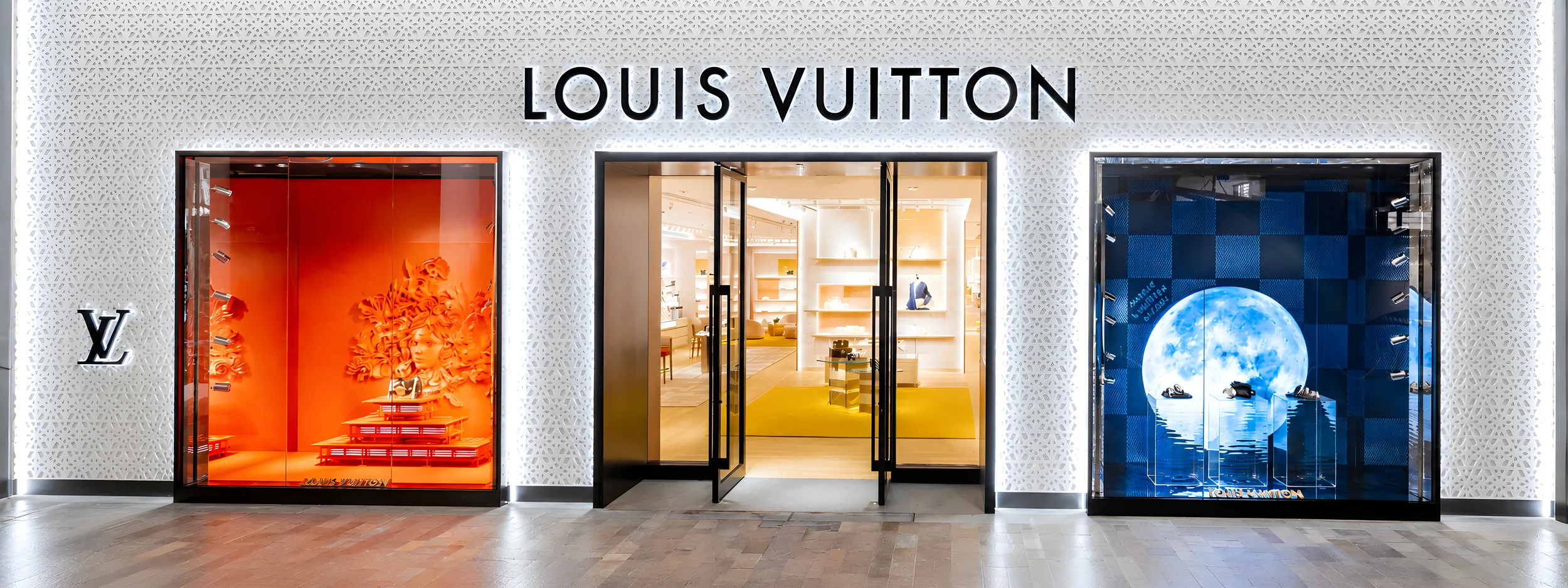 Louis Vuitton store exterior with illuminated display windows showcasing designer accessories and fashion items.