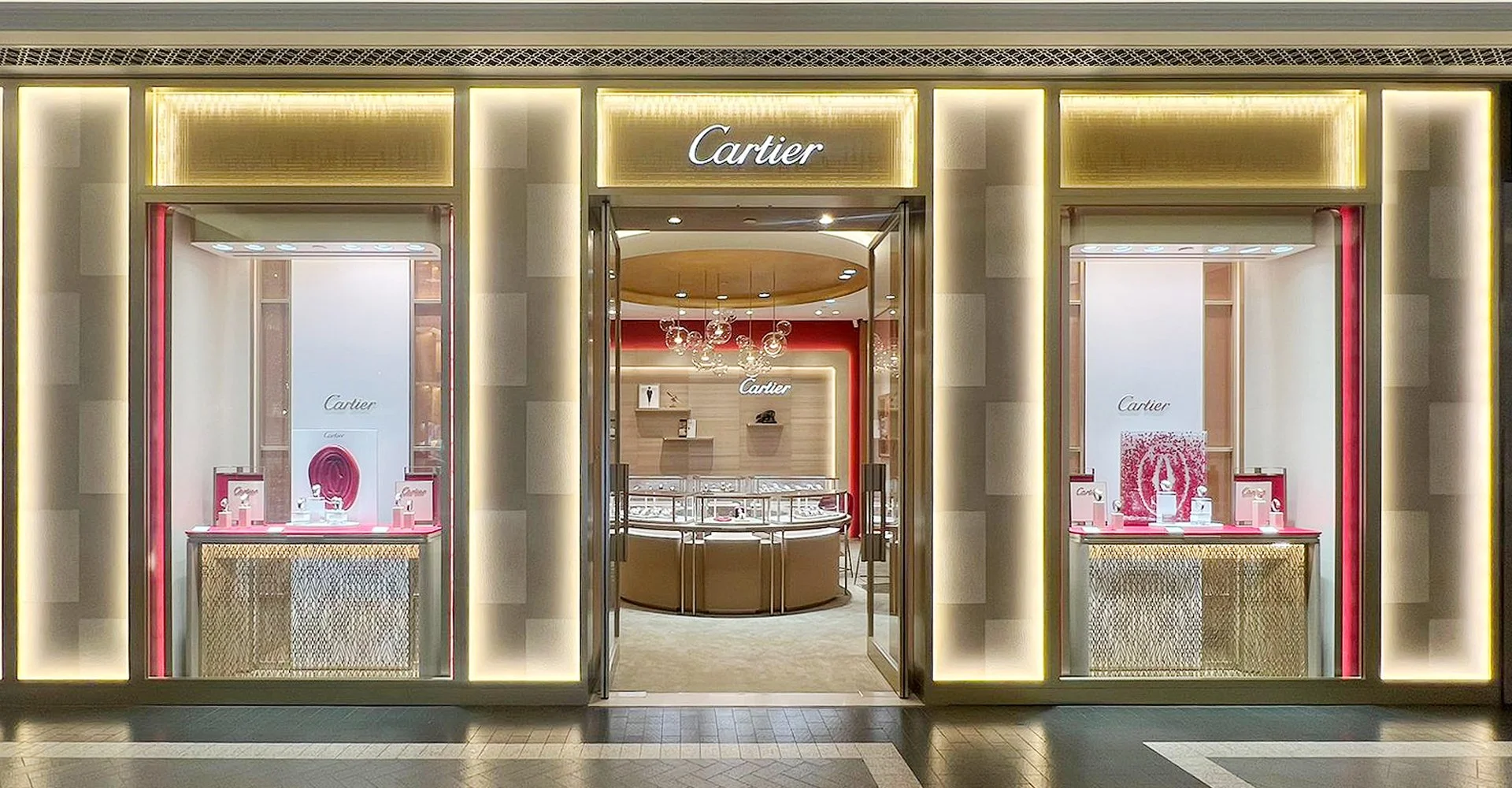 Exterior of a Cartier jewelry store with illuminated signage and display windows showcasing jewelry. Inside, there is a jewelry counter and elegant lighting.