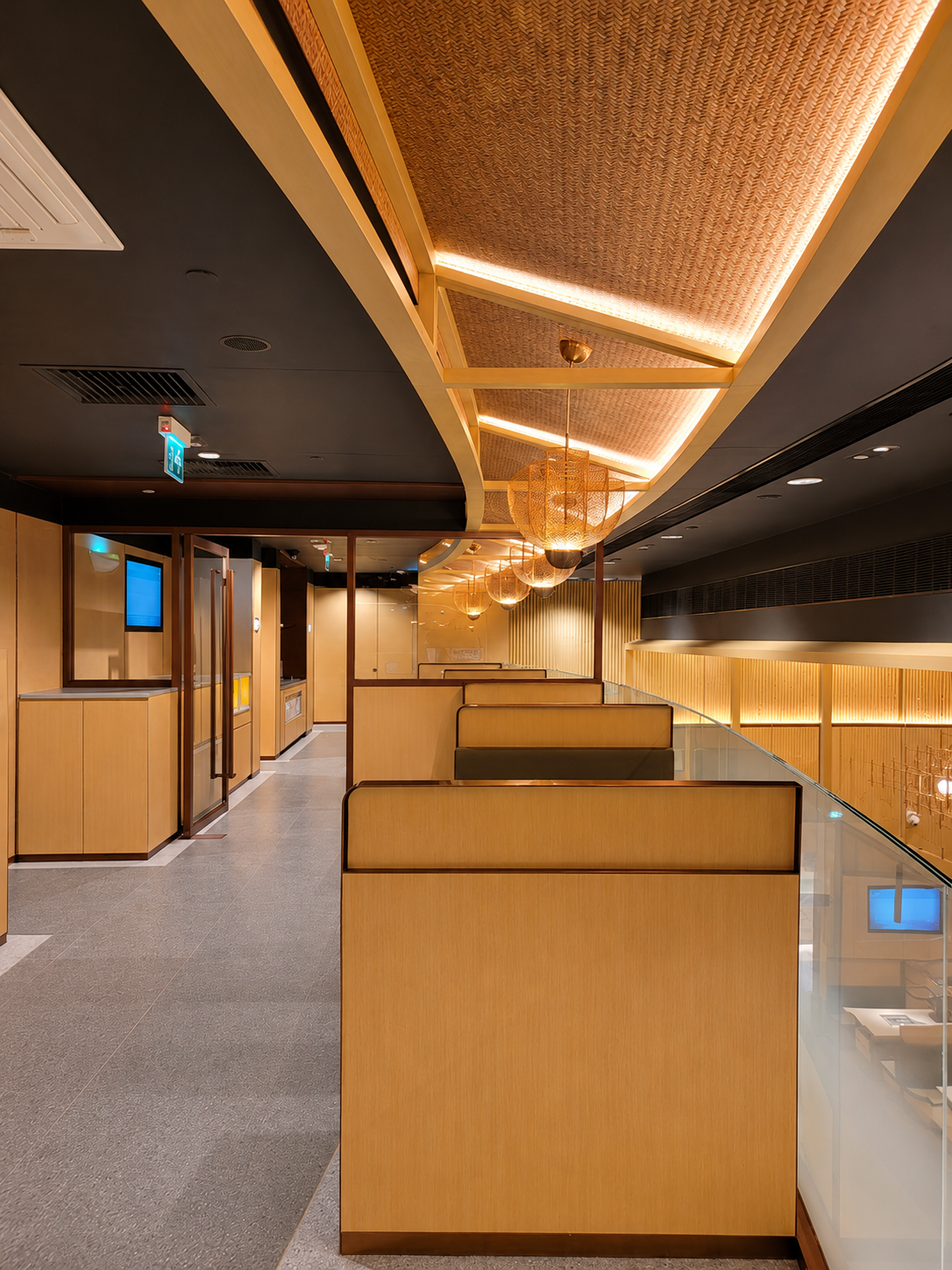Modern indoor space with wooden partitions, hanging lights, and a black ceiling.