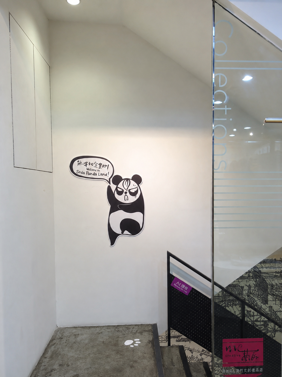 Cartoon panda holding a speech bubble saying 'Welcome to Soda Panda Land!' on a plain white wall near a staircase.