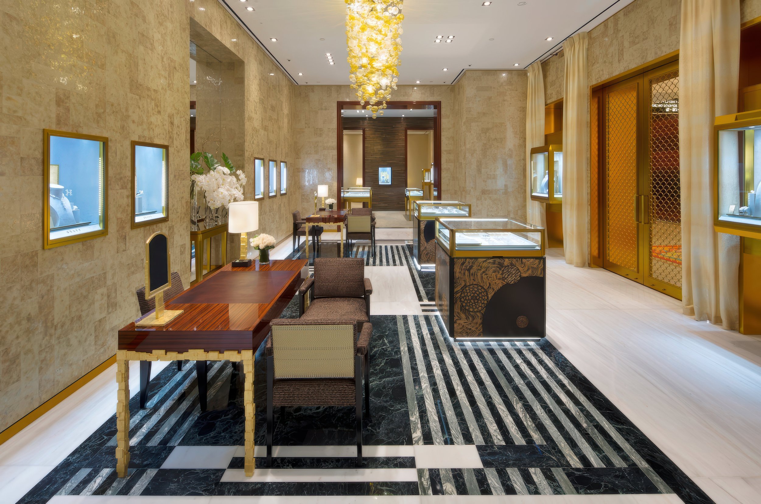 Luxurious jewelry store interior with display cases, seating area, floral arrangements, and warm lighting.