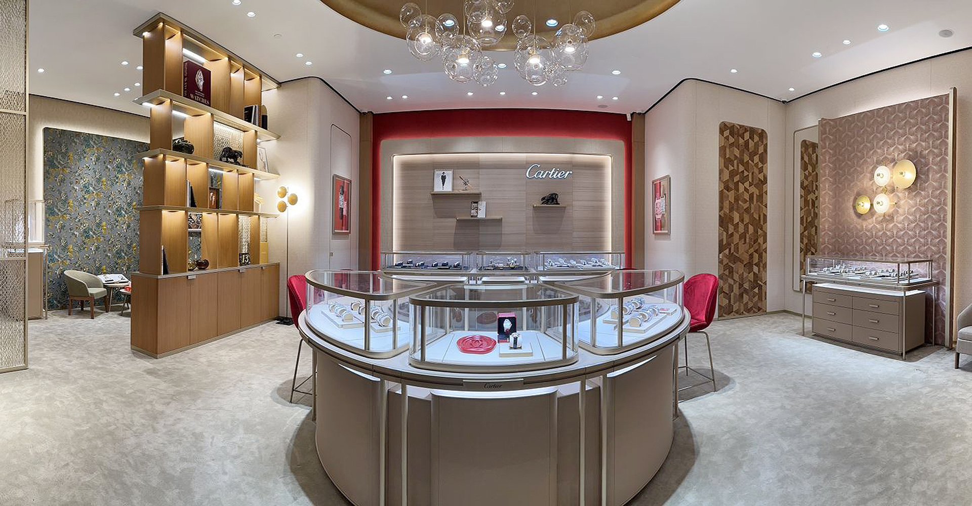 Interior of a jewelry store with display cases showcasing jewelry, Cartier sign on the wall, modern decor, glass chandelier, and seating area.