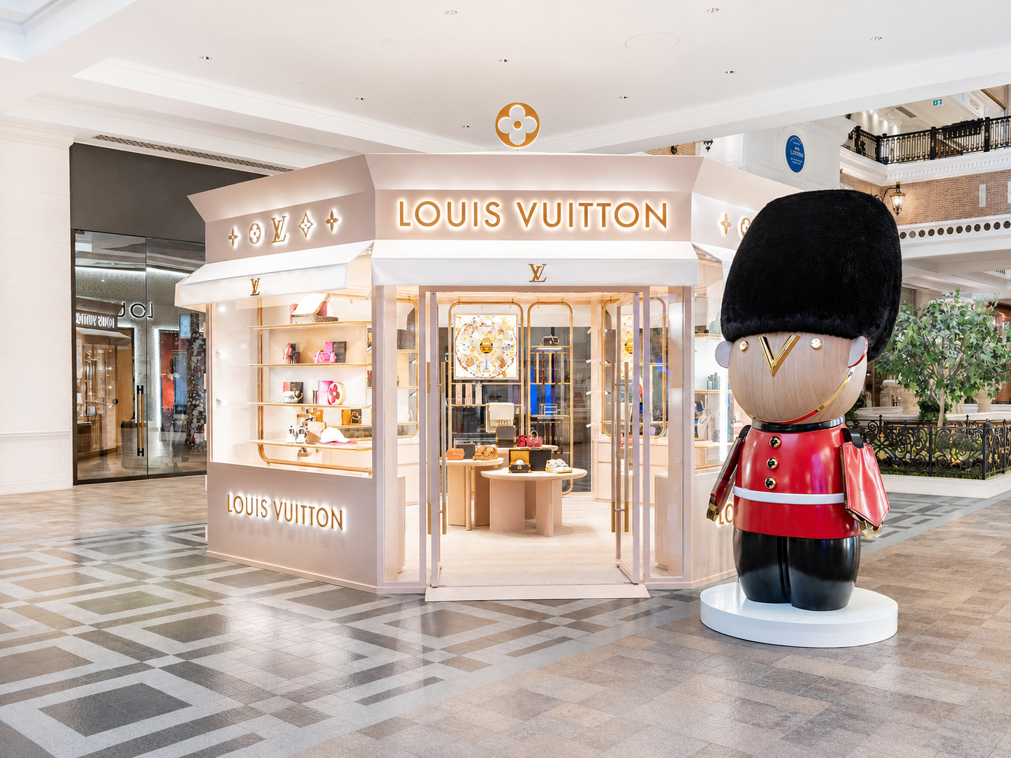 Louis Vuitton store kiosk in a shopping mall with a large mascot figure of a British royal guard in front.