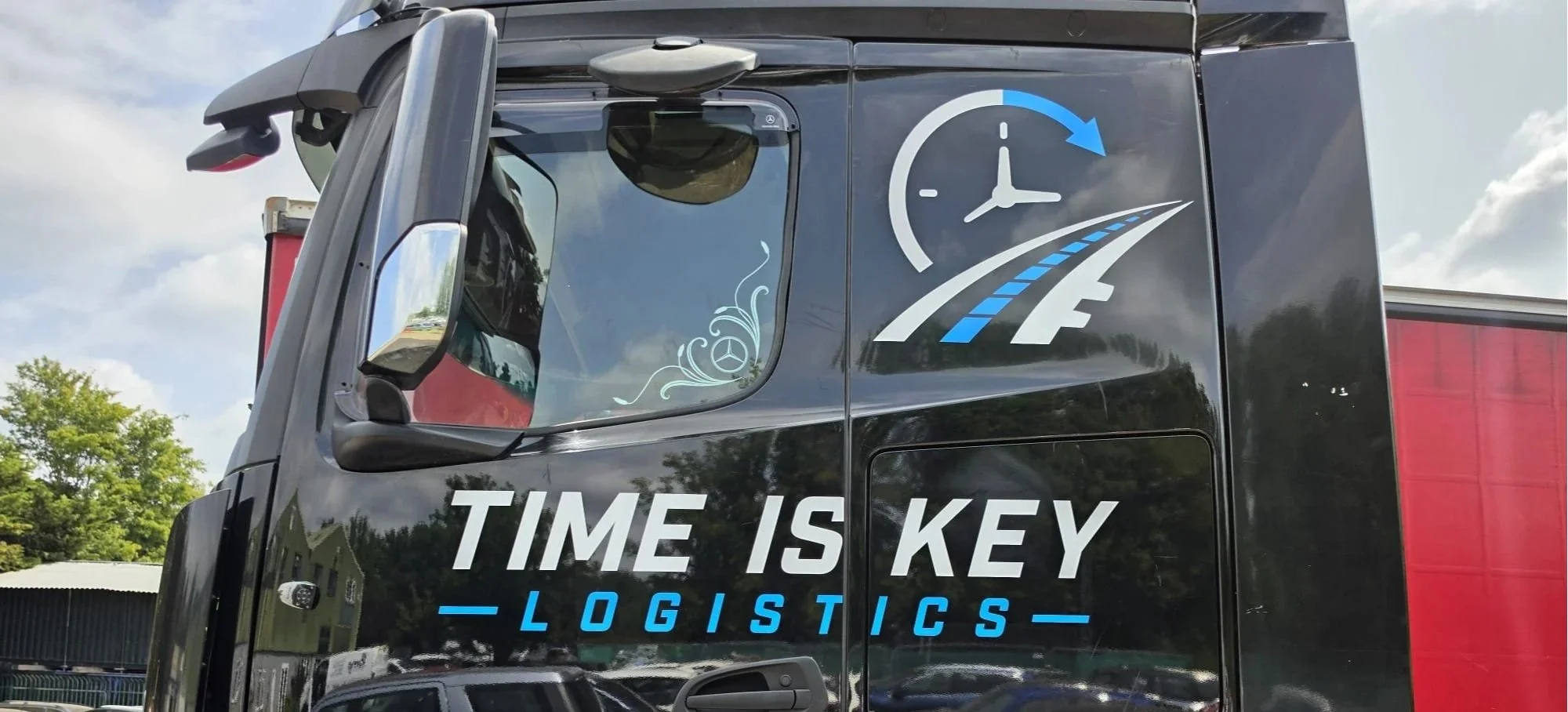 A black truck with logistics company branding, including a large clock and road graphic in white and blue, and the slogan "TIME IS KEY" on the side.