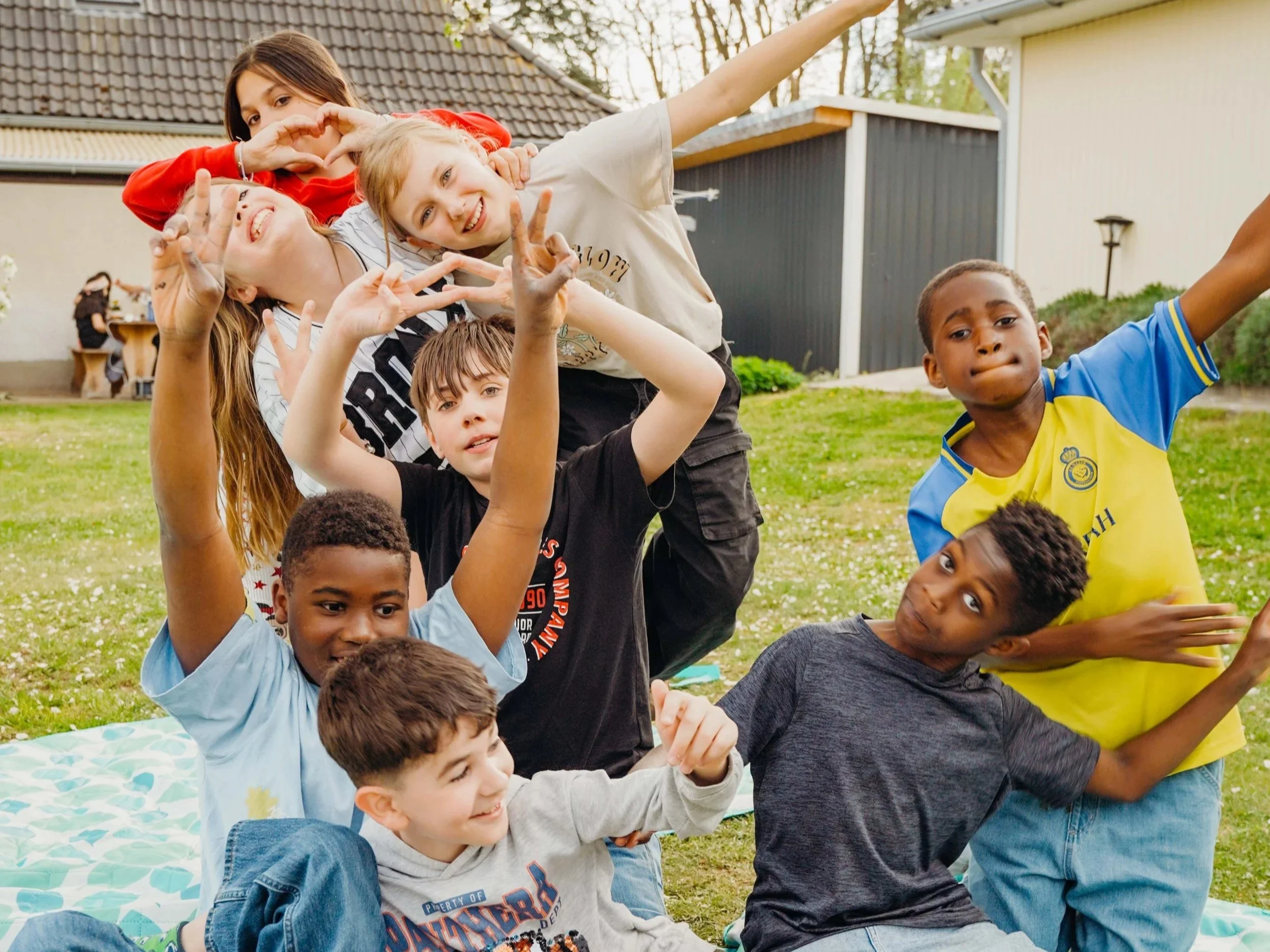 Gruppen von Kindern und Jugendlichen, die im Garten zusammen spielen und Fotos machen.