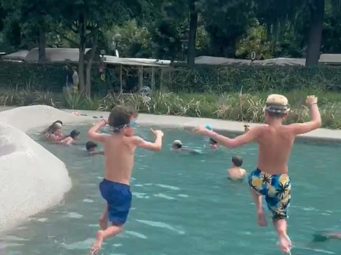 Kinder spielen im Kindergarten im Wasser, wobei sie Spaß haben und springen.