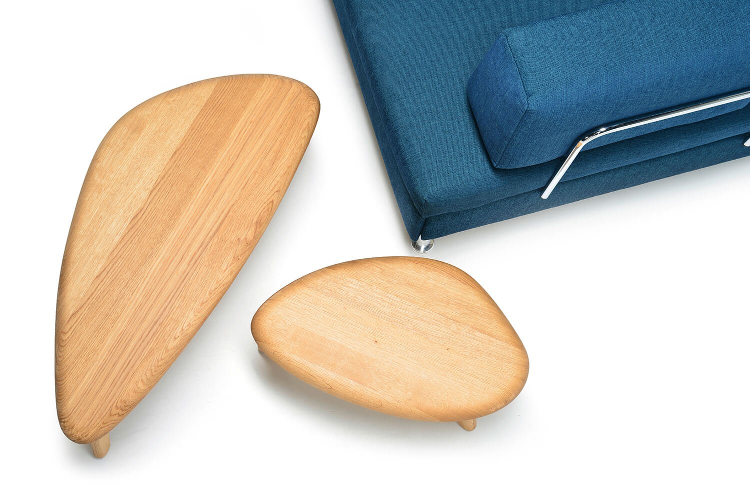 Blick von oben auf zwei Holztische in unterschiedlichen Formen neben einer blauen Couch.