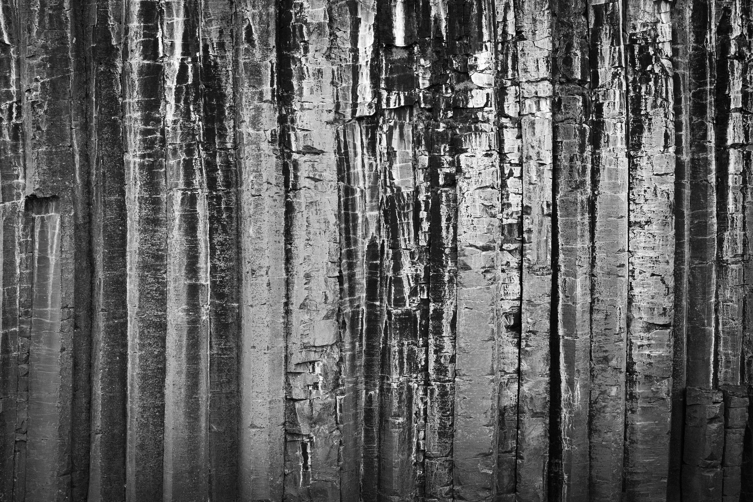 Black and white image of a wooden surface with vertically aligned planks showing varying textures and cracks.