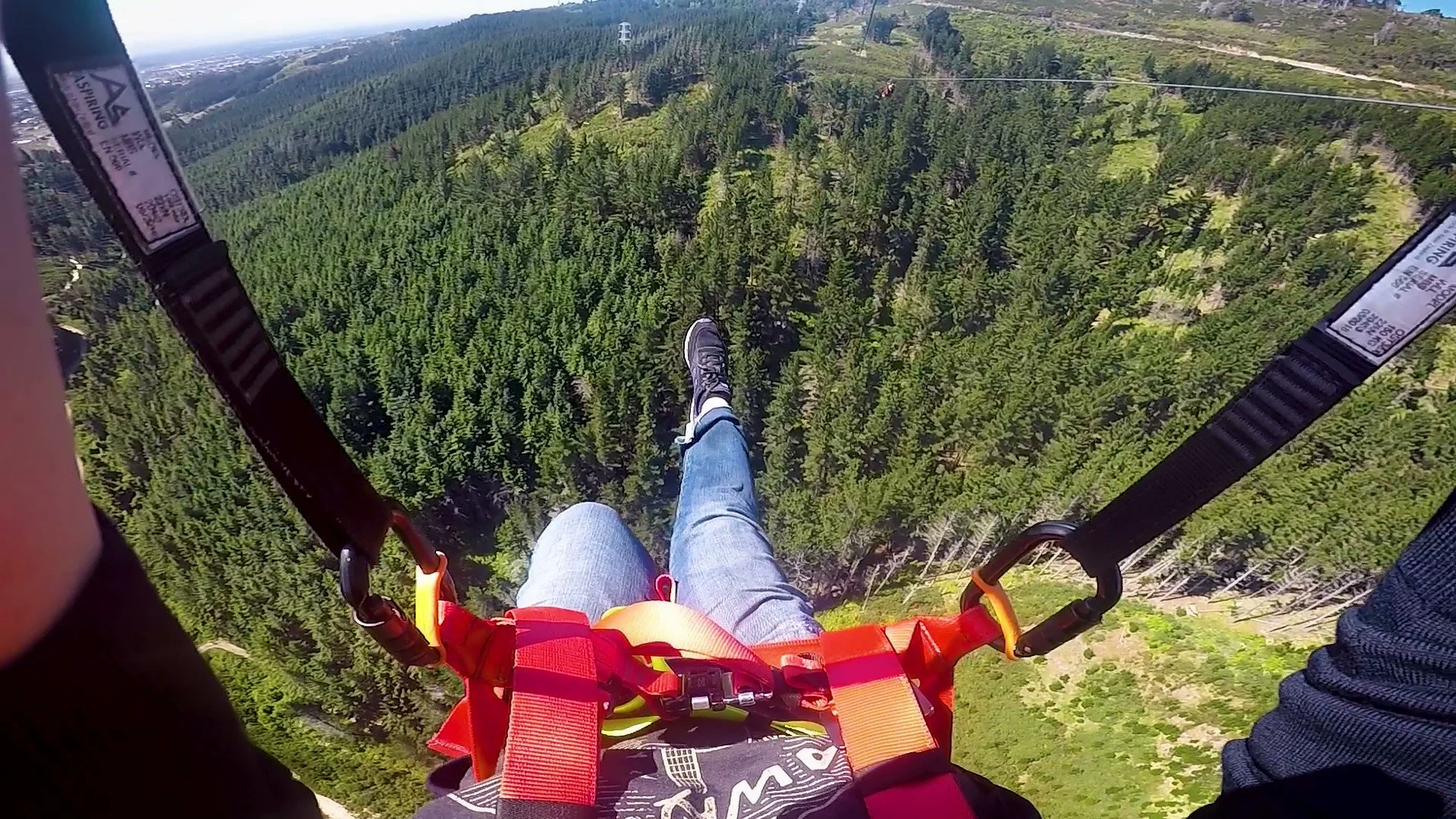 A woman ziplining over a forested landscape