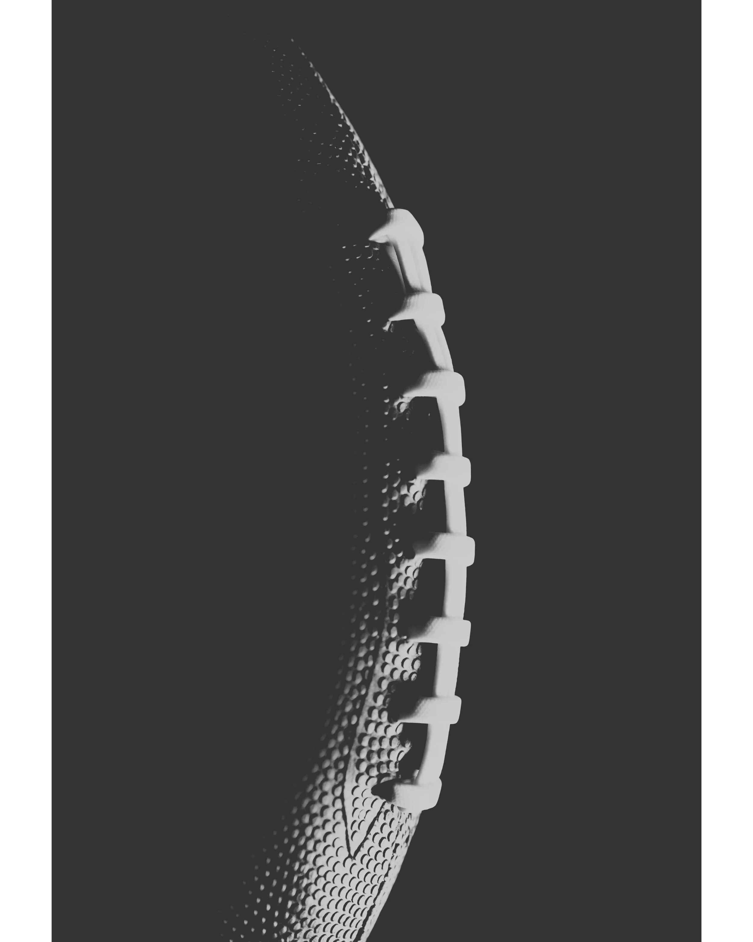 Close-up black and white image of a hockey skate blade with rivets and grip tape, on a textured surface.
