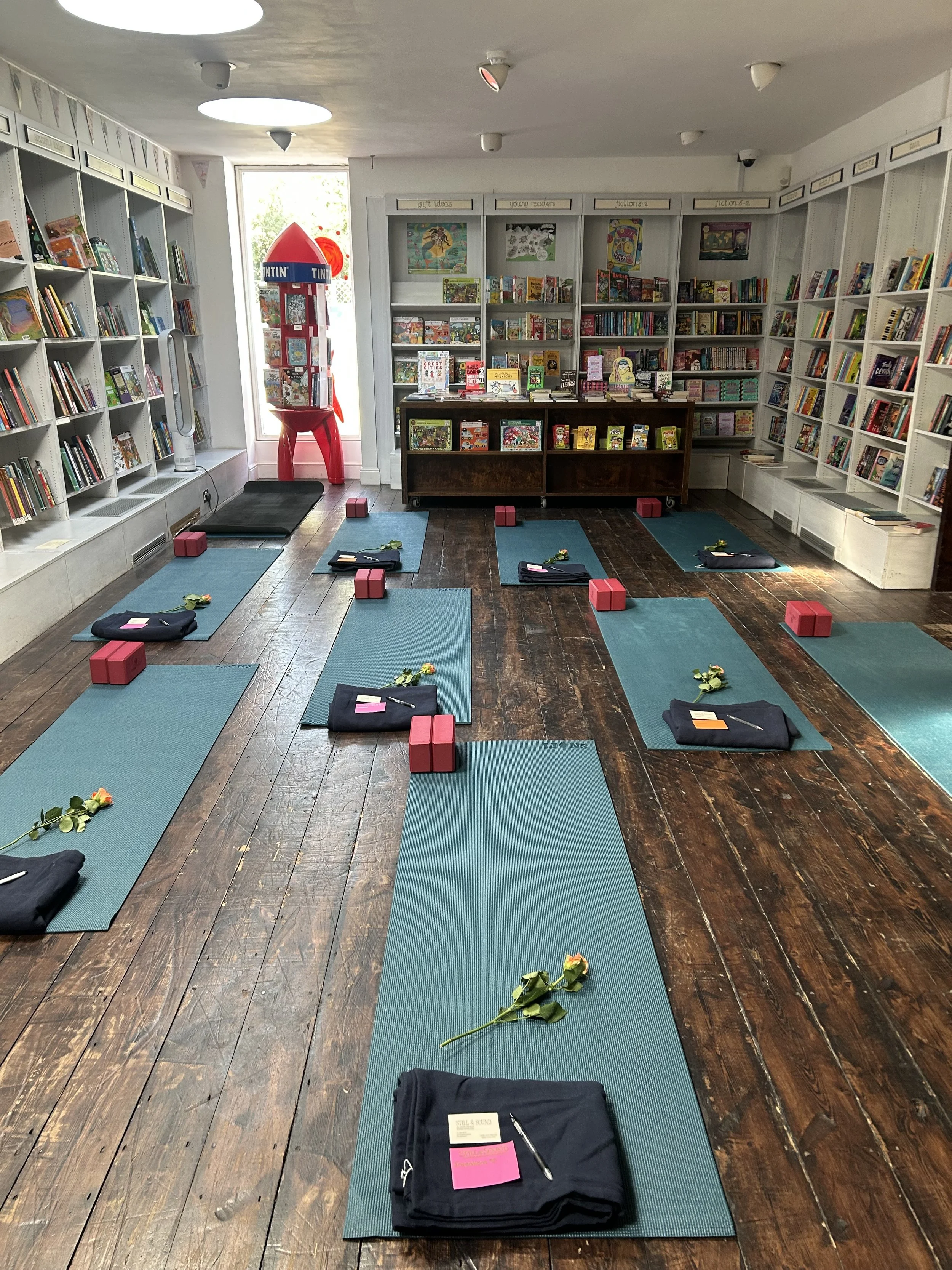 Children’s bookstore interior with bookshelves, a Tintin display, and teal reading mats arranged for a group activity.