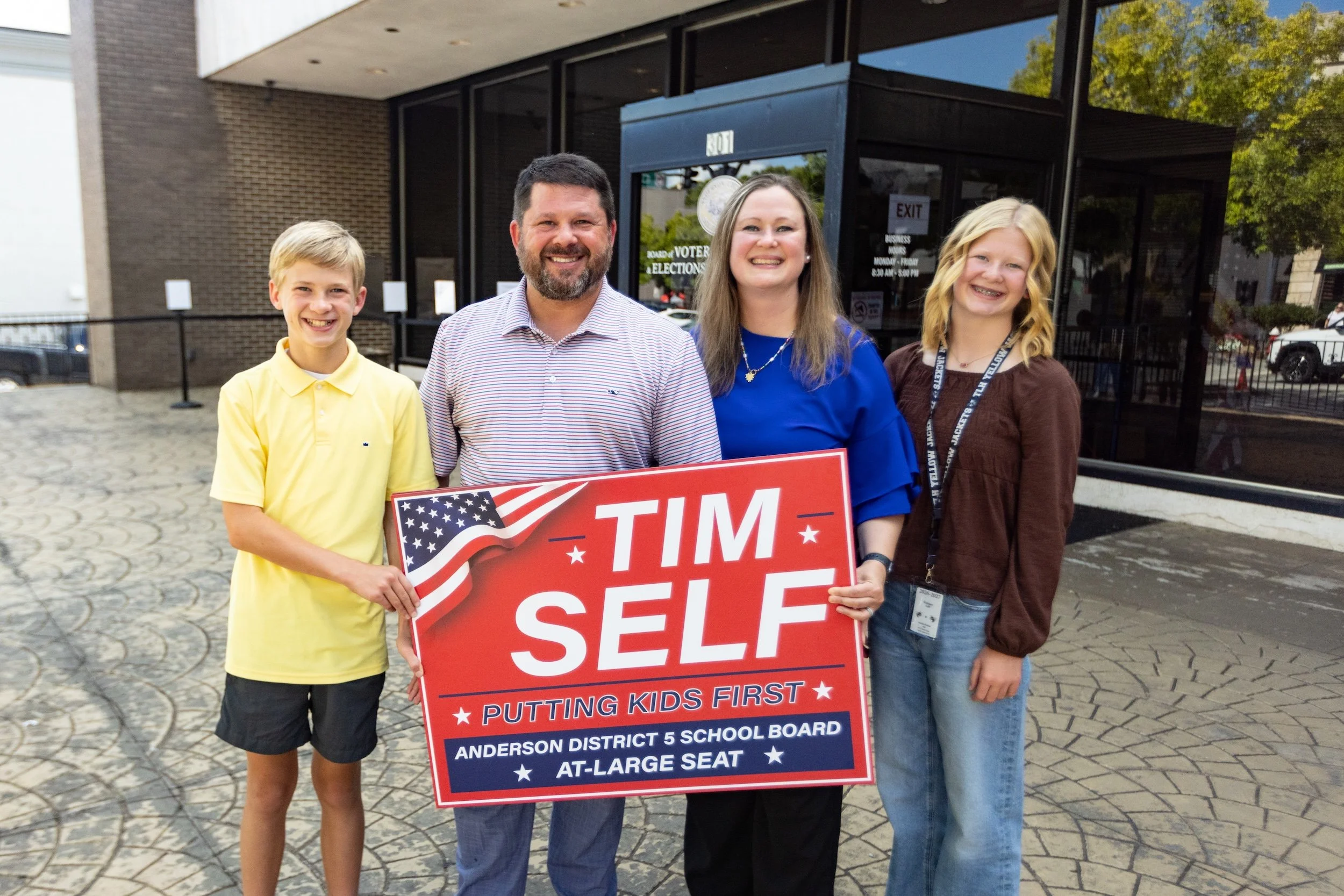 Tim Self and his family holding a sign outside Anderson County Election Commission.