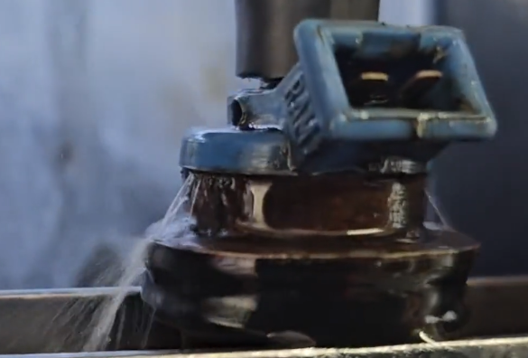 A close-up of an injector being tested at high pressure that has a crack in the housing causing the injector to leak.