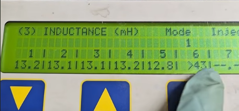 Close-up of an ASNU digital display displaying inductance measurement readings on tested injectors. This shows a failed injector.