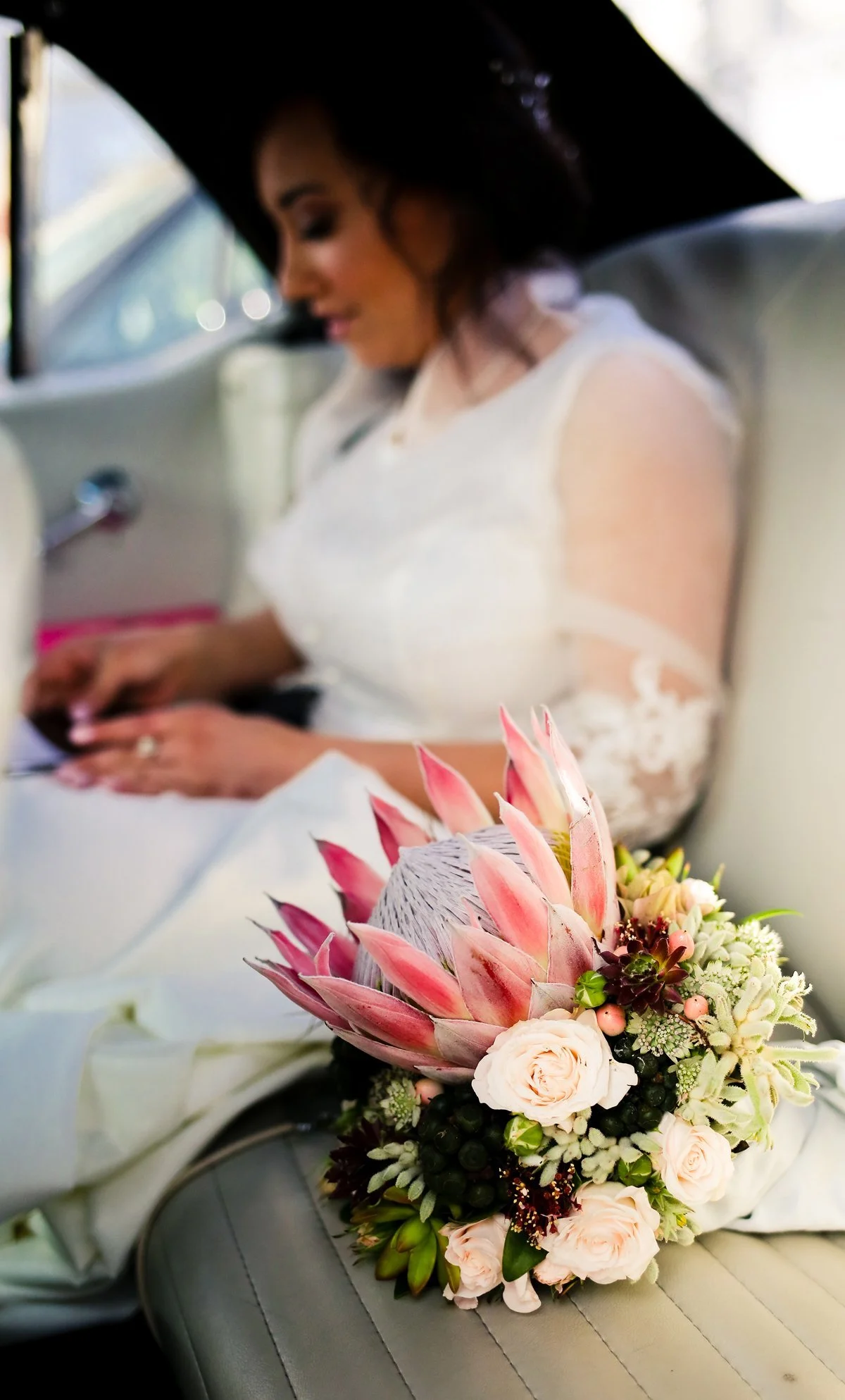 Hochzeitsportrait von Braut im Auto mit Blumenstrauß 